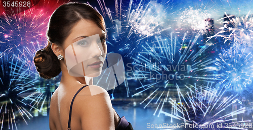 Image of beautiful woman with diamond earring over firework