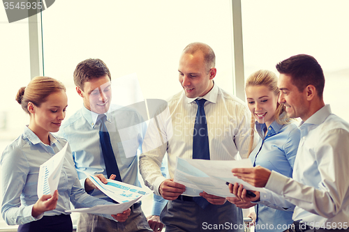 Image of happy business people with papers talkig in office