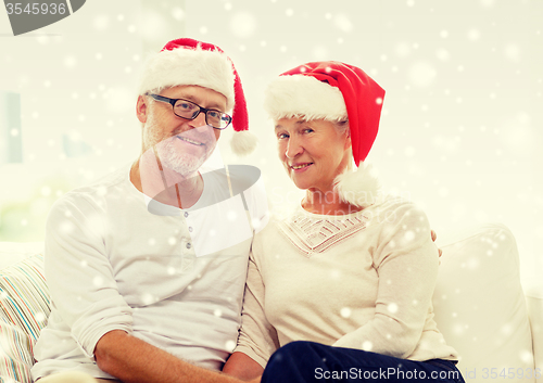 Image of happy senior couple in santa helper hats at home