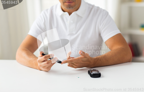 Image of close up of man checking blood sugar by glucometer