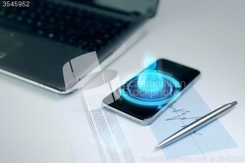 Image of close up of smartphone, laptop and pen on table