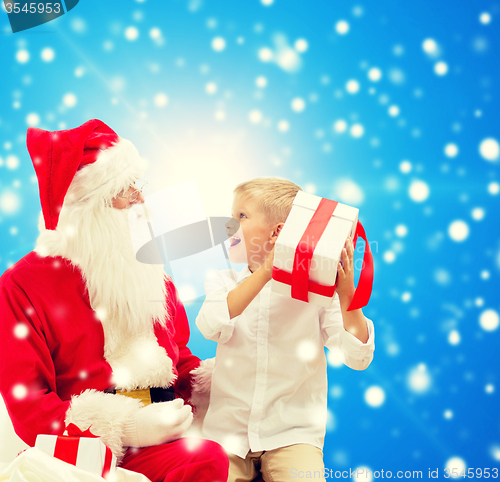 Image of smiling little boy with santa claus and gifts