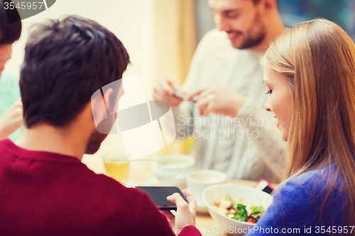 Image of group of friends with smartphones meeting at cafe