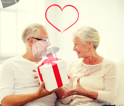 Image of happy senior couple with gift box at home