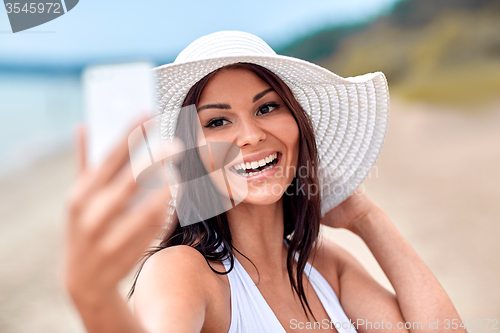 Image of smiling young woman taking selfie with smartphone