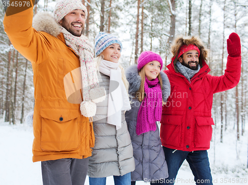 Image of group of friends waving hands in winter forest