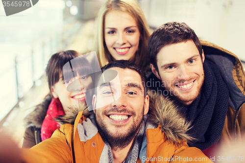 Image of happy friends taking selfie on skating rink