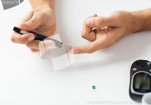 Image of close up of man checking blood sugar by glucometer