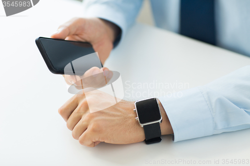 Image of close up of hands with smart phone and watch