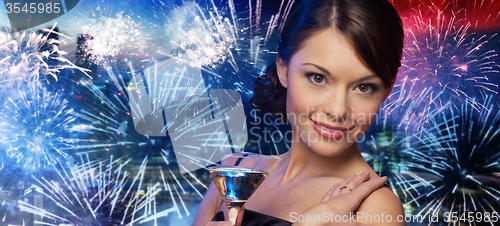 Image of smiling woman with cocktail over firework in city