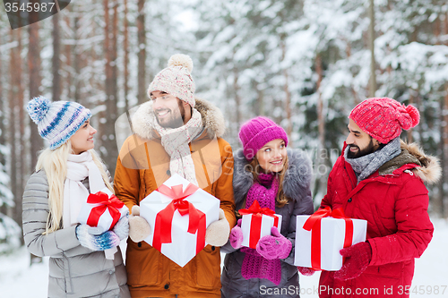 Image of happy friends with gift boxes in winter forest
