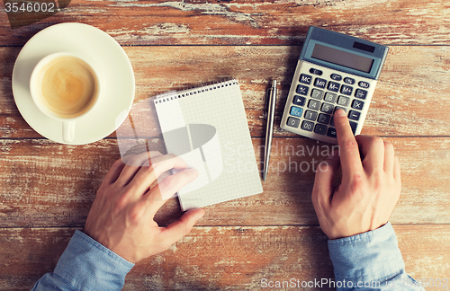 Image of close up of hands with calculator and notebook