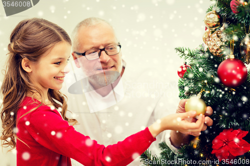 Image of smiling family decorating christmas tree at home