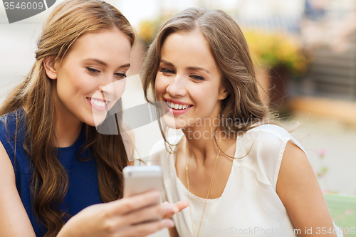 Image of happy young women with smartphone at outdoor cafe