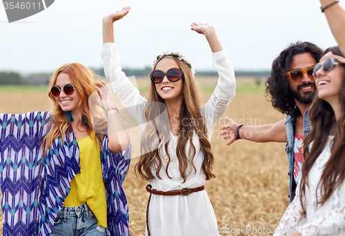 Image of happy young hippie friends dancing on cereal field