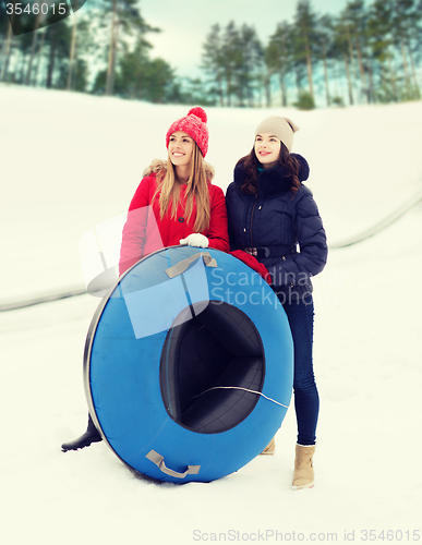 Image of happy girl friends with snow tubes outdoors