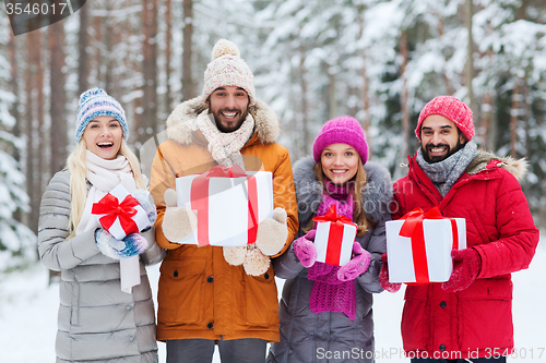 Image of happy friends with gift boxes in winter forest