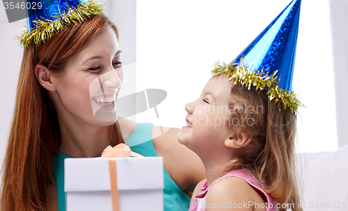 Image of happy mother and child in party caps with gift box