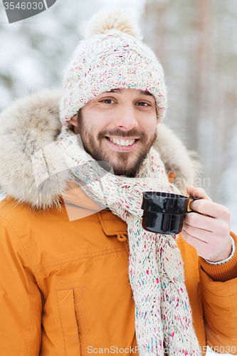 Image of smiling young man with cup in winter forest