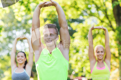 Image of group of friends or sportsmen exercising outdoors