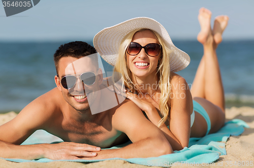 Image of happy couple in swimwear lying on summer beach