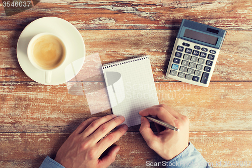 Image of close up of hands with calculator and notebook