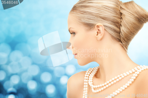 Image of beautiful woman with sea pearl necklace over blue