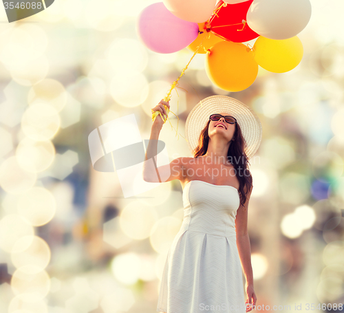 Image of smiling young woman in sunglasses with balloons