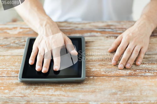 Image of close up of male hands with tablet pc on table