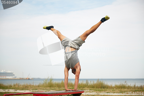 Image of young man exercising on bench outdoors