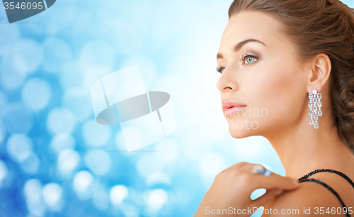 Image of woman with beautiful diamond earrings over blue