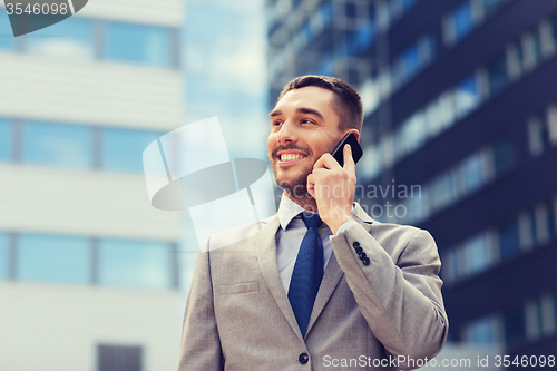 Image of smiling businessman with smartphone outdoors