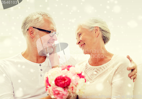 Image of happy senior couple with bunch of flowers at home