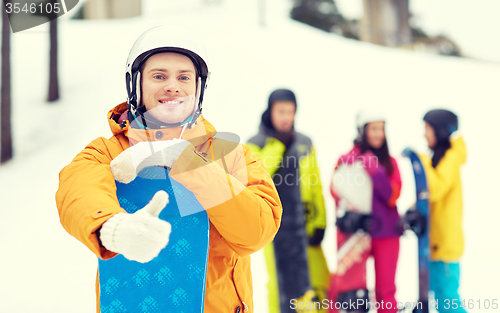 Image of happy young man with snowboard showing thumbs up