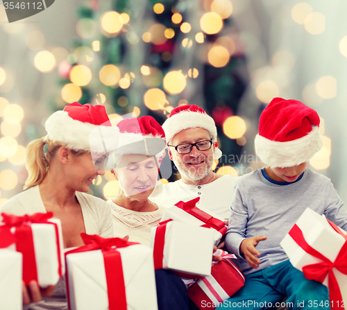 Image of happy family in santa helper hats with gift boxes