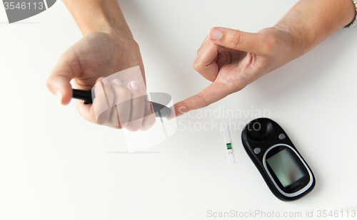 Image of close up of woman making blood test by glucometer