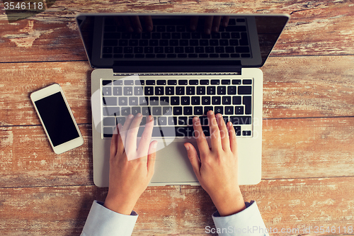 Image of close up of hands with laptop and smartphone