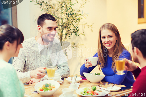 Image of happy friends meeting and having dinner at cafe