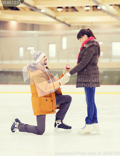 Image of happy couple with engagement ring on skating rink