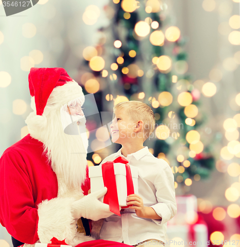 Image of smiling little boy with santa claus and gifts