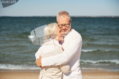 Image of happy senior couple hugging on summer beach