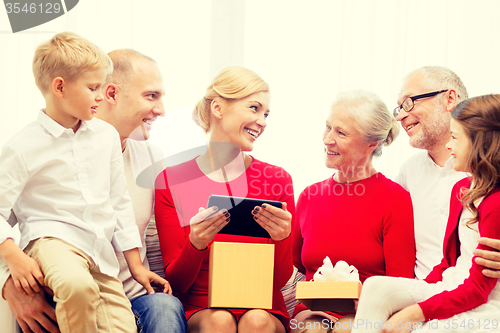 Image of smiling family with tablet pc and gift box at home