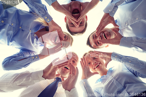 Image of smiling group of businesspeople standing in circle