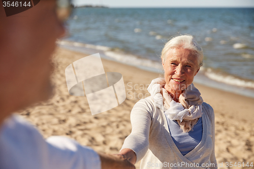 Image of happy senior couple holding hands summer beach