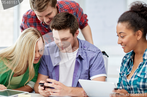 Image of group of happy students with smartphone at school