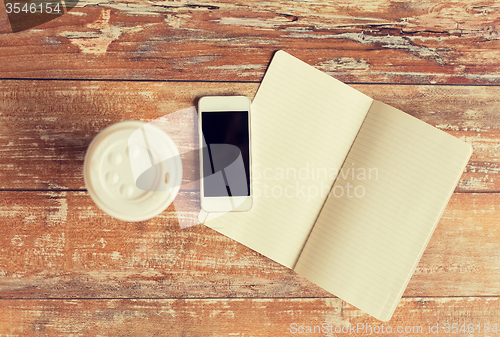 Image of close up of notebook, coffee cup and smartphone