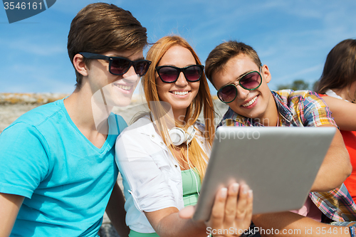 Image of group of smiling friends with tablet pc outdoors