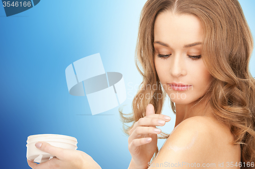 Image of smiling woman cleaning face skin with cotton pad