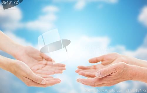 Image of close up of senior and young woman hands