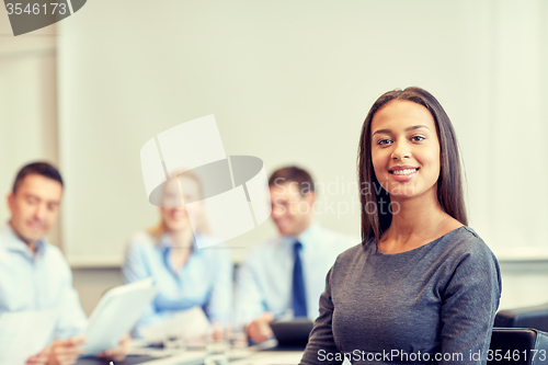 Image of group of smiling businesspeople meeting in office